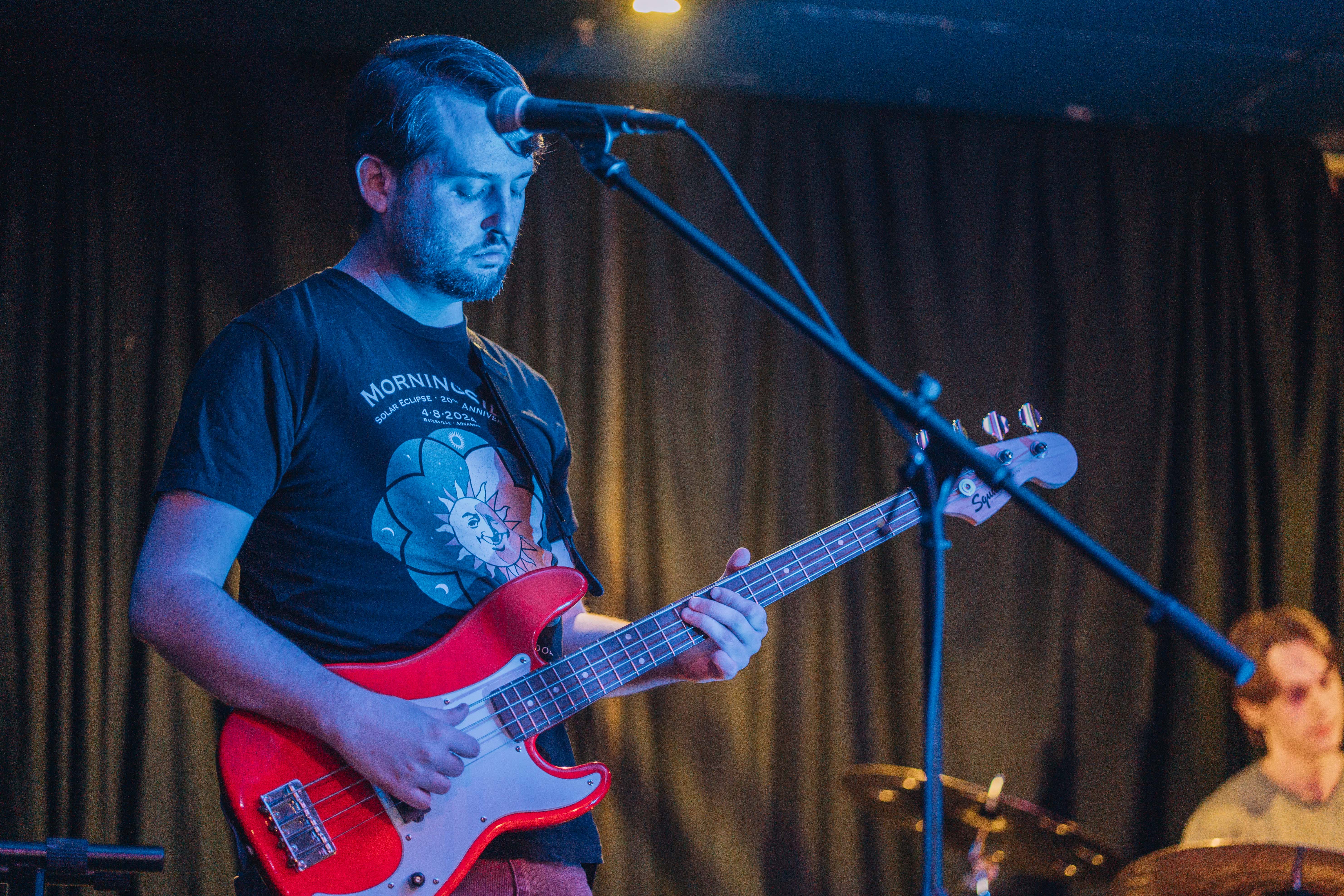 Sean playing red bass, heavily contrasted with blue stage light